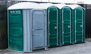 ada porta potty near a fence with other porta potties